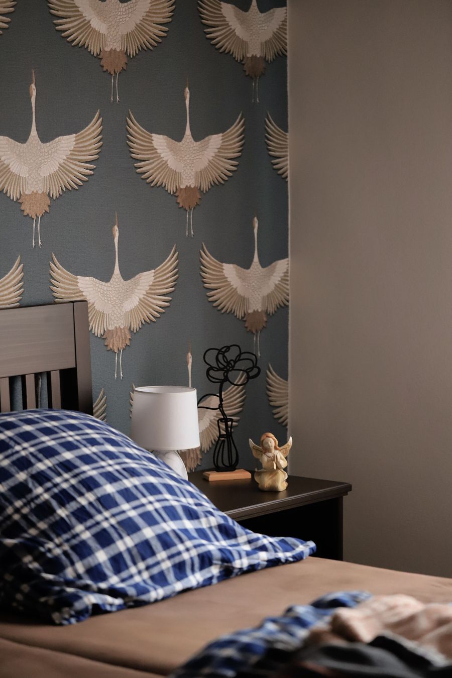 Bedroom accent wall papered in a flying-crane print on a slate blue background beside a bedside lamp