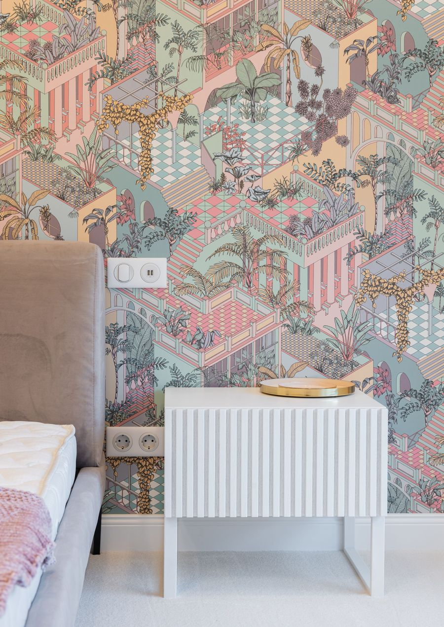 Pastel isometric garden mural wallpaper behind a white fluted nightstand and upholstered bed